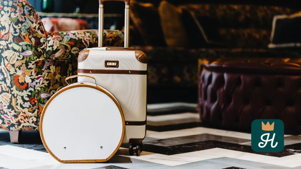 Valise vintage dans un élégant salon d’hôtel de charme à Séville, entre fauteuil tapissé et pouf en cuir, évoquant luxe et raffinement. 